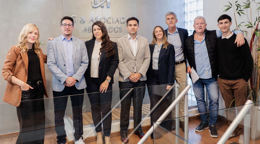 El equipo de LG & Asociados en la recepción del estudio, junto al logo institucional