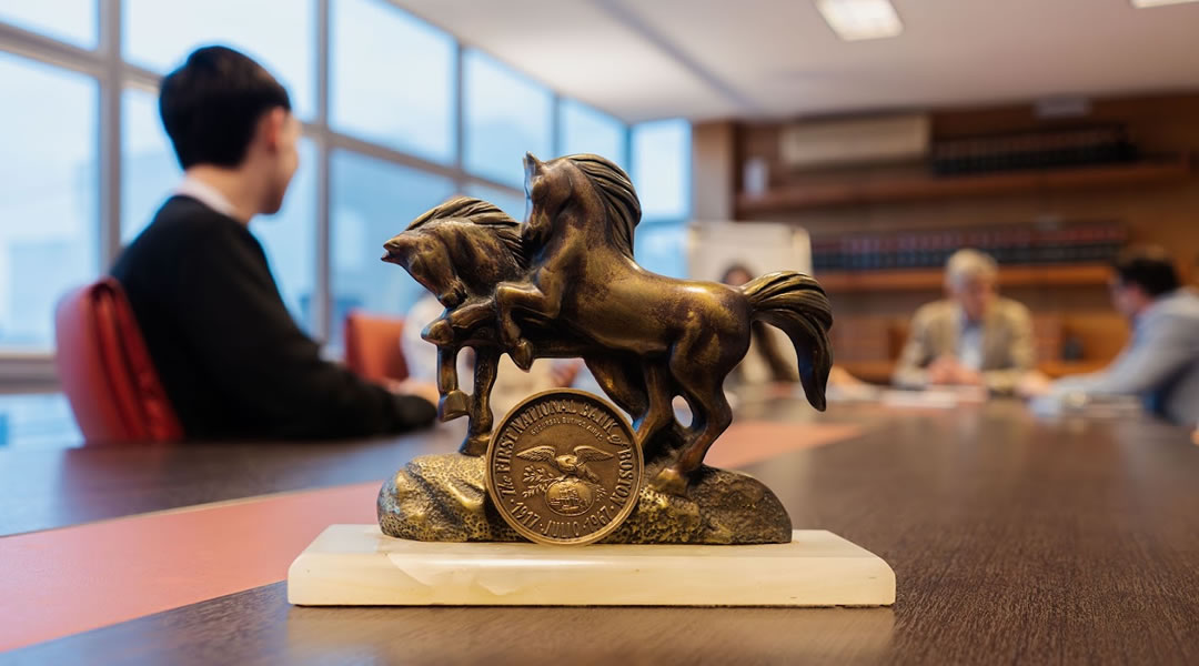 Escultura de caballos sobre la mesa de reuniones, con el equipo del estudio trabajando de fondo
